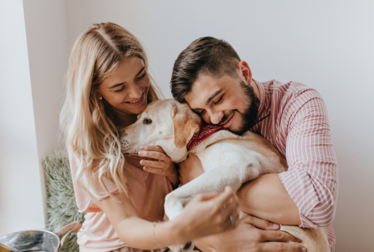 Couple hugging with happy dog