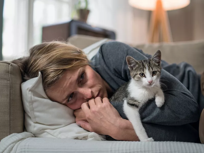 Woman indoors on sofa at home feeling stressed