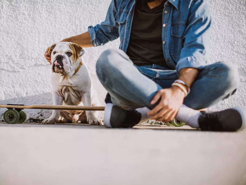 Man with skateboard sitting with dog